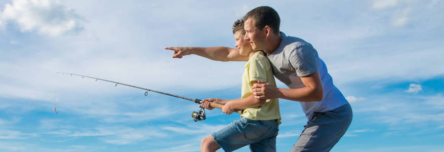 在蓝天的衬托下，儿子拿着一根鱼竿，父亲在远处表演