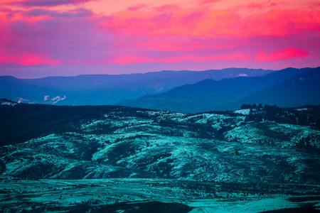 五颜六色的日落在山丘上粉红色的云。 普罗旺斯的田野景观覆盖着雪日落紫光。