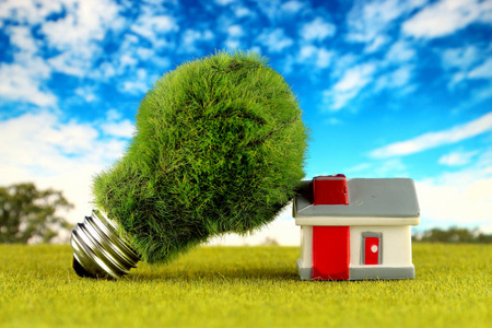 绿色环保灯泡和微型房子。 可再生能源概念。 家庭节能的电价。