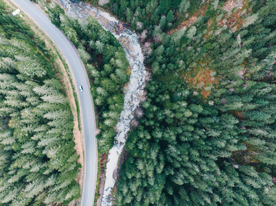 鸟瞰道路与河流旁边的山与永远绿色的树木。 公路旅行概念