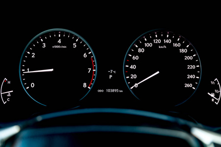 关闭汽车仪表板与转速表和速度计指示燃油水平和测量发动机速度和速度在黑色背景下。