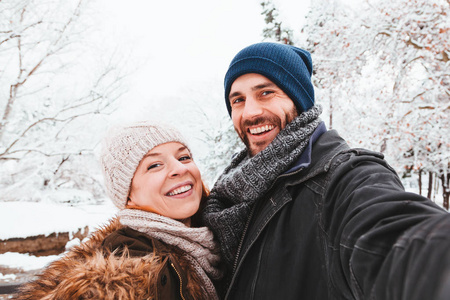 一对年轻夫妇在下雪天在公园里自拍