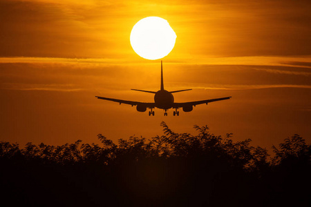 一架靠近太阳的飞机的轮廓，背景是美丽的红云