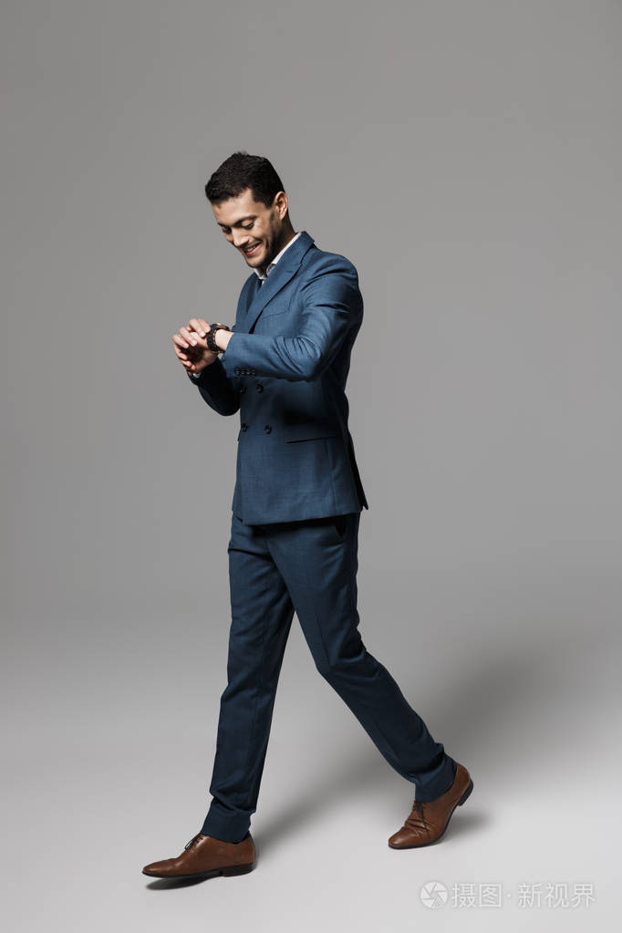 30多岁的阿拉伯男子穿着正式西装,在灰色背景下孤独行走