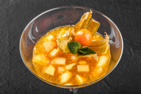 果浆从芒果和桃子装饰薄荷和菲沙利在一个玻璃在暗石背景。夏季甜点