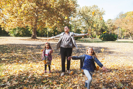 幸福的家庭在公园美丽的秋天玩得很开心。 母亲和她的女儿享受大自然。