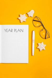 年计划写在一个笔记本上，上面有干净的床单，放在钢笔旁边，上面装饰着白色的图案，冬天的饼干。 规划一个新的一年概念。 俯视图平躺