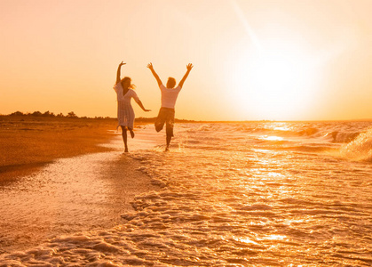 幸福的一对在日落时在海滩上奔跑