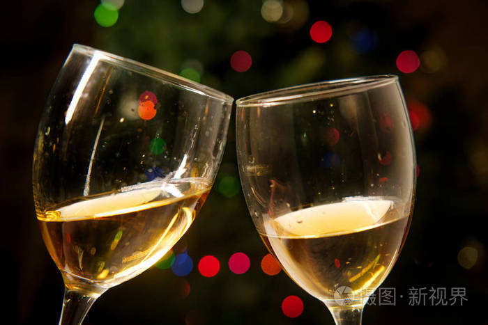 快乐的假期两个酒杯碰撞在一起圣诞灯光背景