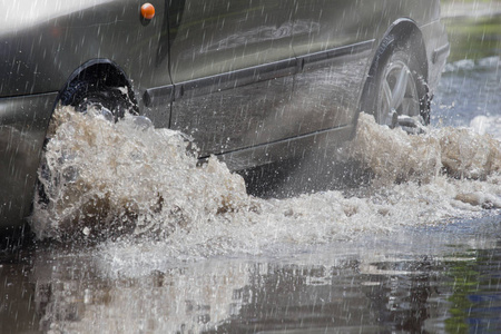 运动汽车雨大水坑从车轮喷水。
