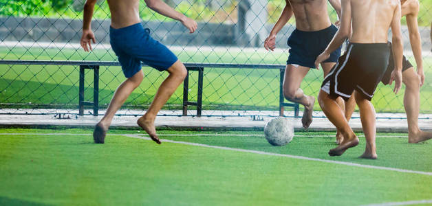 足球运动员不穿运动衫和赤脚做陷阱和控制球射到球门。 足球运动员互相踢球。