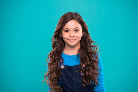 孩子快乐可爱的脸与可爱的卷曲发型立场在蓝色背景照片