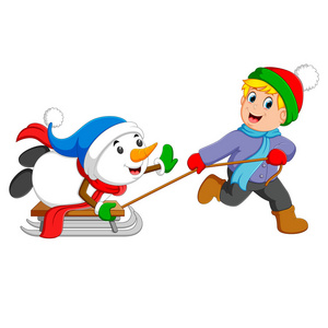 一个兴奋的男孩正把雪人拉到冰车上照片