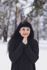 冬雪森林里穿毛衣的年轻美丽的黑发女孩