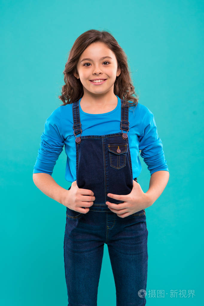 长头发的小女孩.孩子快乐可爱的脸与可爱的卷发站在蓝色的背景.