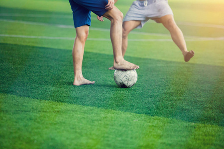 足球运动员不穿运动衫和赤脚做陷阱和控制球射到球门。 足球运动员互相踢球。