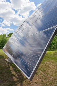替代太阳能量概念。 大太阳能电池板元素对绿色自然和晴空的垂直侧视照片