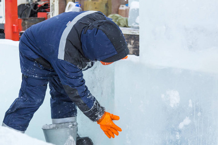 冰城工地的安装工用湿雪覆盖冰板的接缝