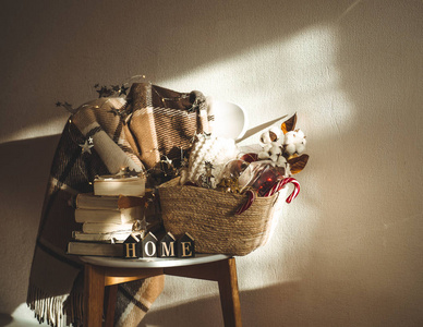 冬天温暖的毯子放在椅子上, 上面有一篮子圣诞装饰品书和带绳灯。家。冬季阅读。房子