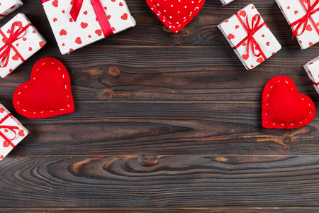 情人节或其他节日手工礼物纸与红心和礼品盒在假日包装。 礼物盒在深色木桌上的顶部视图与复制空间空空间的设计。