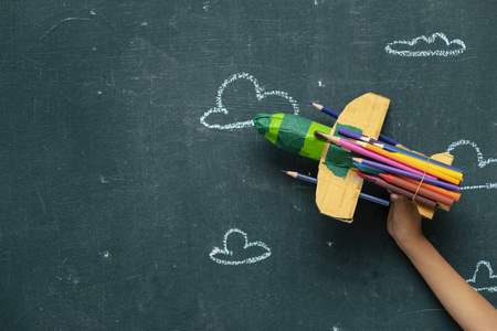 回到学校的概念与纸火箭，由铅笔在黑板背景上