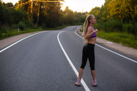 跑步的女人在郊区的路上慢跑之前热身。