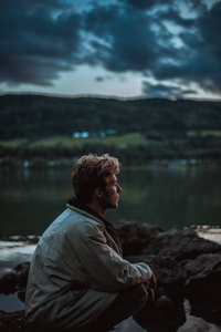 在挪威森林附近的湖边，坐在巨石中的人