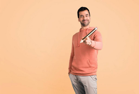 穿着粉红色运动衫的男人，在赭色背景上拿着一支大铅笔