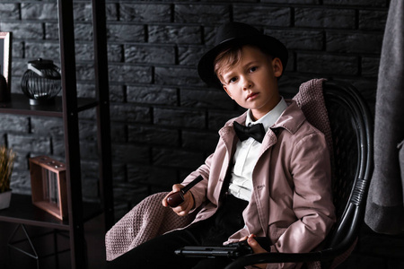 侦探游戏可爱的小侦探,拿着烟斗坐在扶手椅上照片