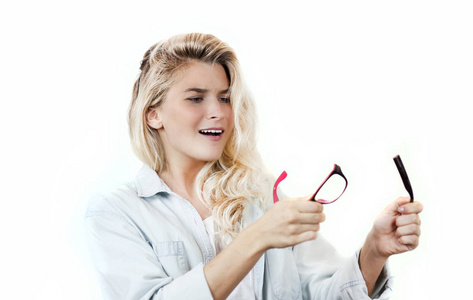 年轻漂亮的女孩，双手戴着破碎的眼镜和镜片，背景是白色的。视力健康的概念