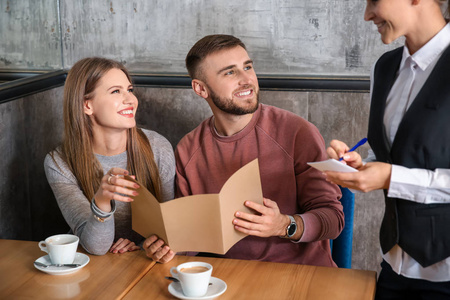服务员从餐馆的年轻夫妇那里点餐照片