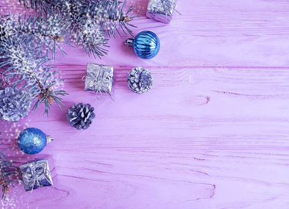 圣诞树树枝，球，粉色木制背景上的礼品盒