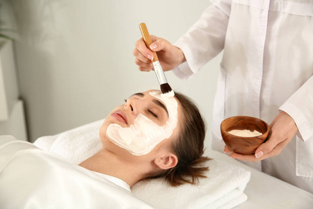 美容师在美容院给年轻女子敷面膜照片