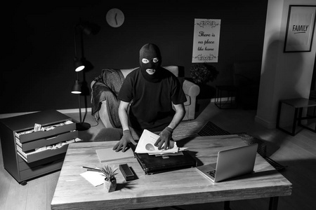 男性小偷在室内,通过安全摄像头观看照片