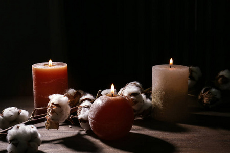 木制桌子上美丽的燃烧蜡烛和棉花