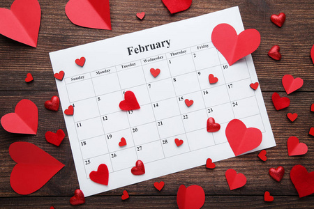 红色的心与白色的二月日历木桌