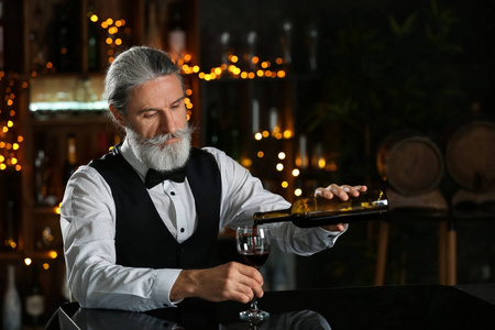 高级酒吧老板把酒倒进酒吧的杯子里照片