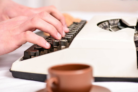 男性手型故事或报告使用白色复古打字机设备关闭。写常规。复古打字机的概念。手打字复古书写机。老打字机和作者手