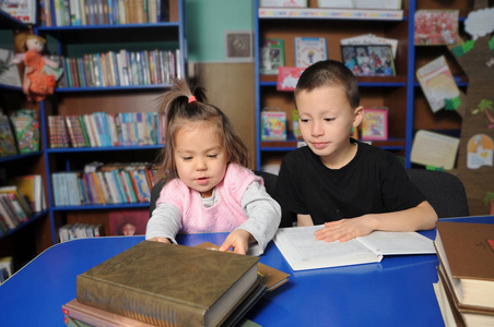 图书馆里的孩子们读有趣的书。 小女孩和男孩一起学习