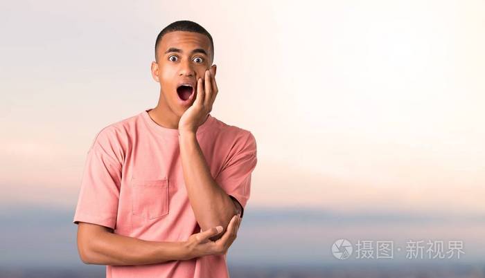 黑暗的皮肤男人惊讶和震惊同时看向右日落背景下的表情情感