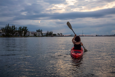 冒险女孩皮划艇在大西洋，在一个充满活力的多云日落。 拍摄于美国西佛罗里达钥匙。