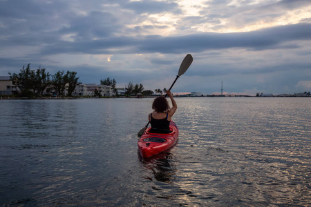 冒险女孩皮划艇在大西洋，在一个充满活力的多云日落。 拍摄于美国西佛罗里达钥匙。
