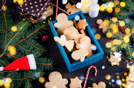 圣诞作文，许多姜饼在木箱，杉树枝和礼品盒在黑暗的木桌上。 度假概念背景图复印空间