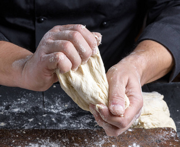 s hands knead white wheat flour dough, close up