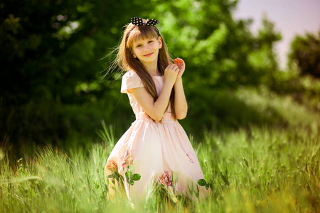 一幅美丽的小女孩的肖像，穿着优雅的裙子，在绿色的夏