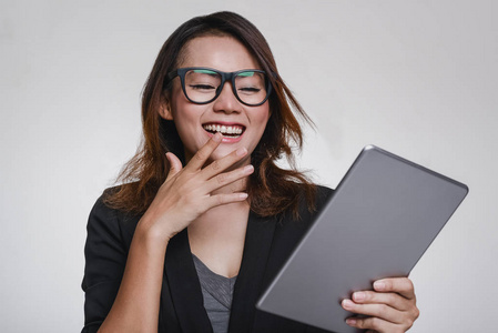 亚洲女人看着他的ipad,心情愉快,专注于脸.照片