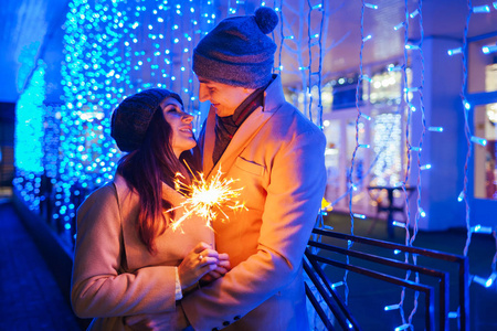 年轻有爱的夫妇在节日的光照下燃烧着火花。 圣诞节和新年概念