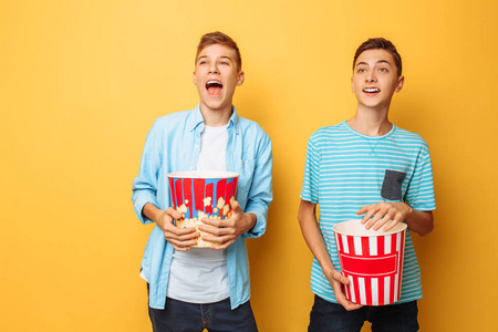 两个兴奋的漂亮青少年看有趣的电影和吃爆米花的形象