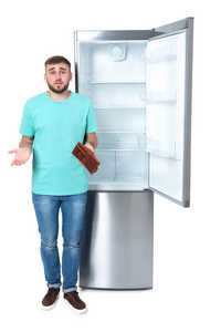 在白色背景的空冰箱边钱包没钱的年轻人