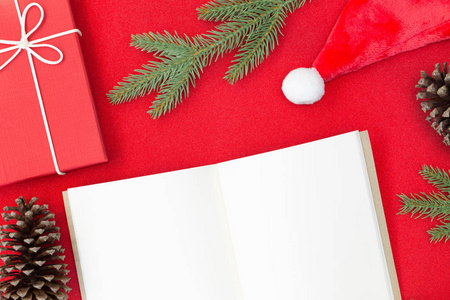 圣诞节和新年快乐作文的俯视图，礼品盒，松果，红底的杉树枝和你的文本复制空间白纸